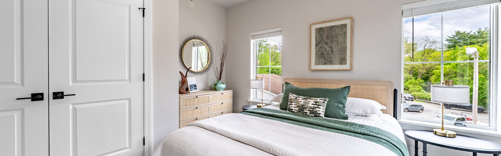 Primary bedroom inside The Ridge apartment with large windows and natural light