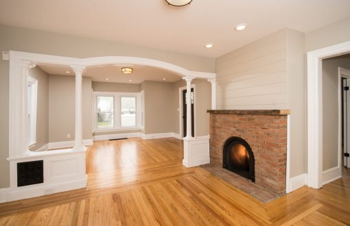 Undecorated living room with fireplace and arched doorway separating rooms